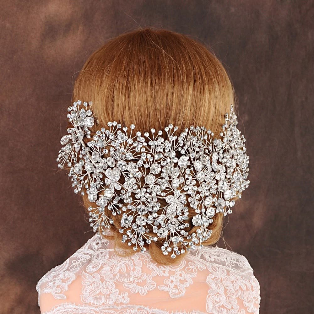 A crystal bridal headpiece fanned across a low chignon, worn over a lace gown