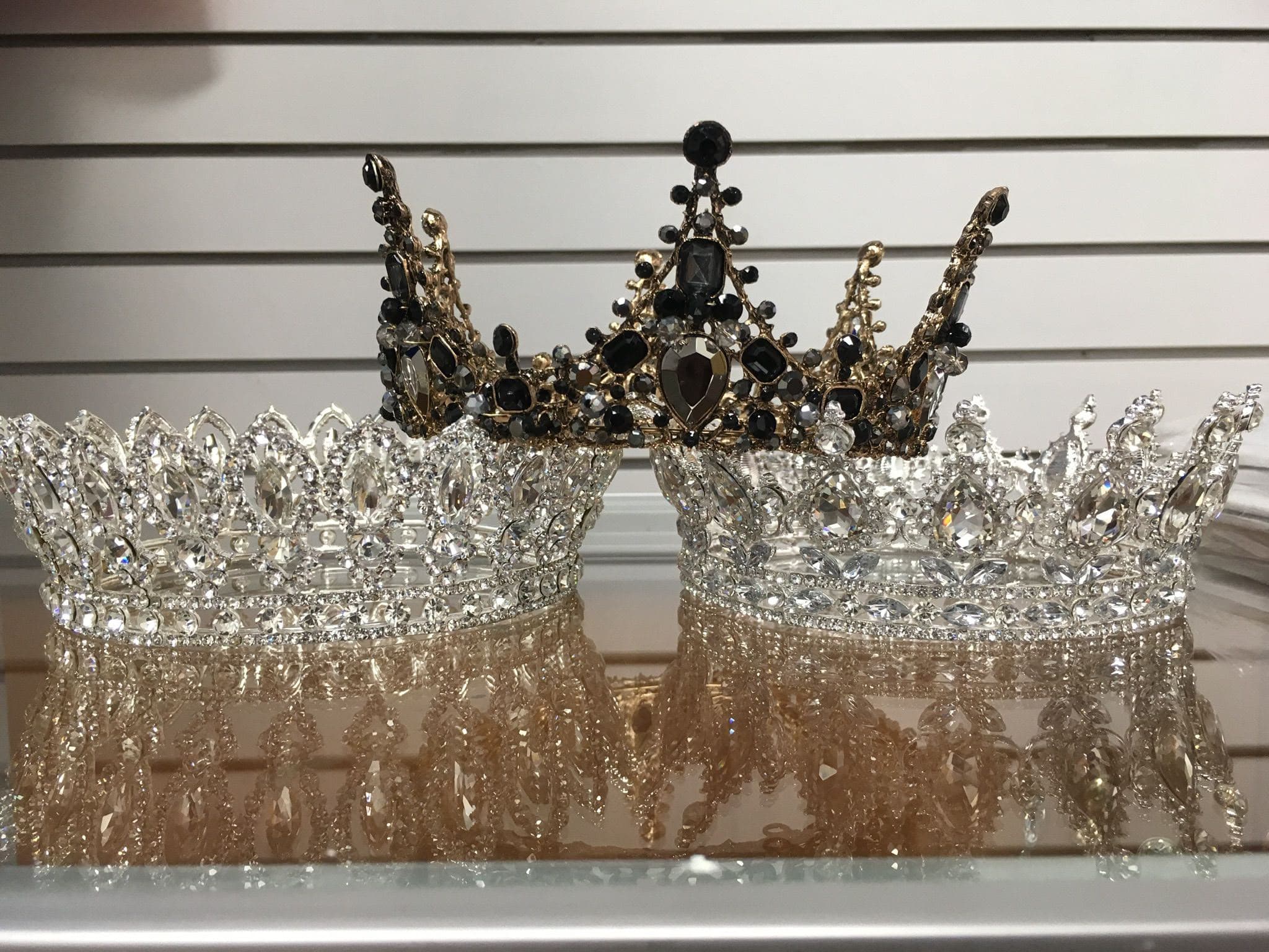 Crystal and gold bridal crowns displayed on a mirrored shelf