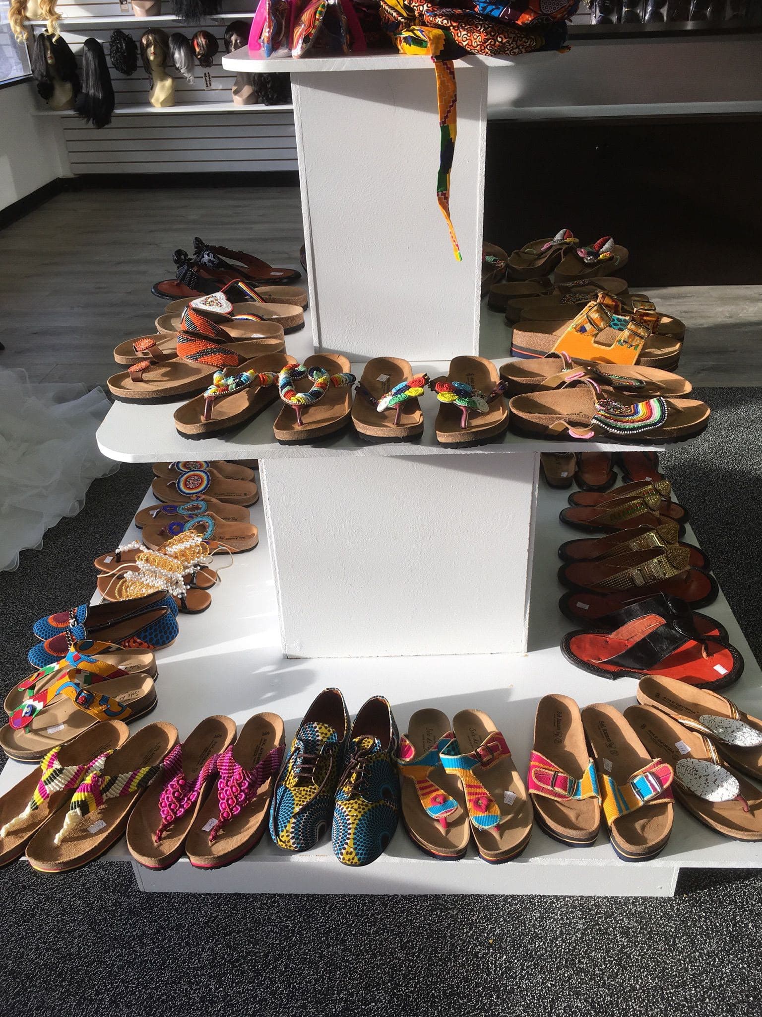 Hand-beaded African-inspired sandals and slippers arranged on display risers
