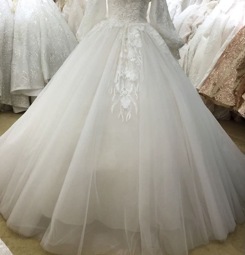 A full-skirted ivory ball gown with lace sleeves on a mannequin in the showroom