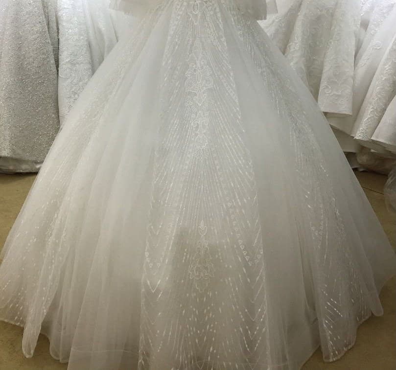 A beaded ivory ball gown with sheer sleeves on a mannequin in the showroom